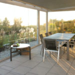 Table de jardin haut de gamme sous un coucher de soleil devant une maison luxueuse